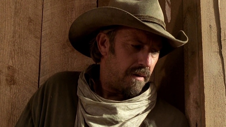 Charley (Kevin Costner) appuyé contre un mur en bois dans 