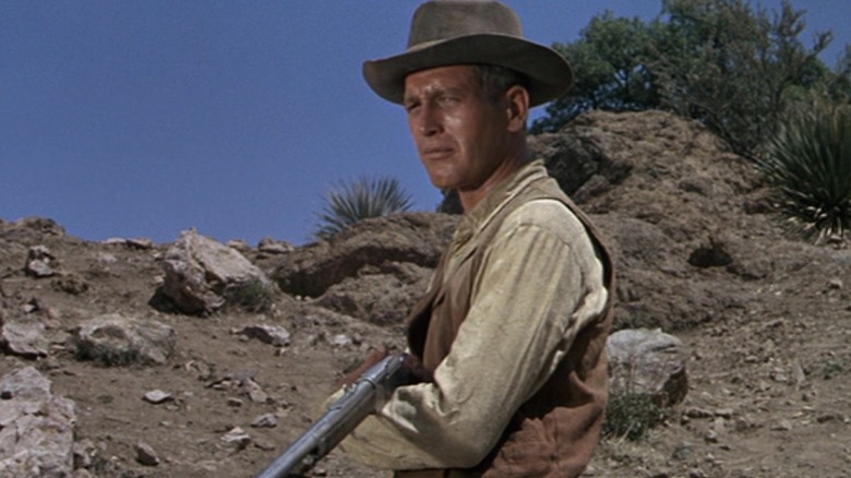 John tenant une arme dans le désert dans Hombre
