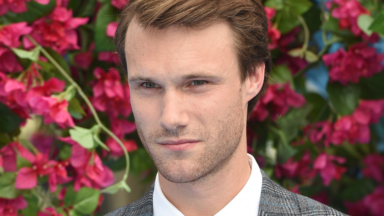 Hugh Skinner devant des fleurs
