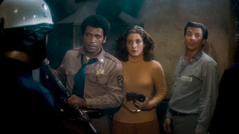 Bishop, Wilson et Leigh discutent avec un policier casqué, tous armés, dans Assault on Precinct 13 (1976)