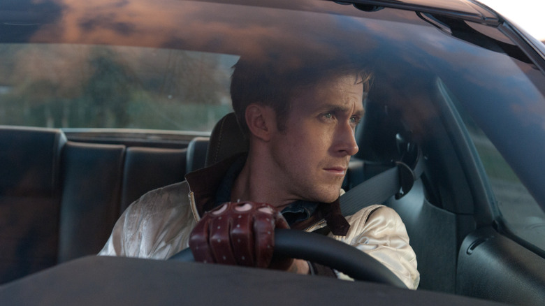 Le Conducteur regardant par la vitre côté conducteur de sa voiture, gant rouge sur le volant, dans Drive (2011)