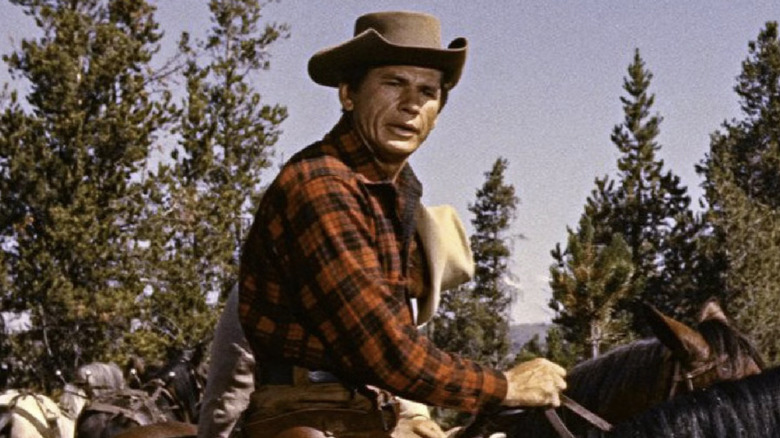 Reb portant une chemise à carreaux rouge et un chapeau de cowboy sur un cheval 