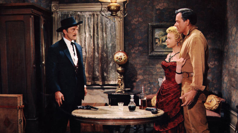 Doc Holliday, Kate Fisher et Johnny Ringo debout autour d'une table dans Gunfight à l'OK Corral