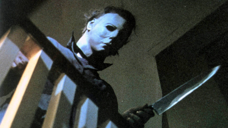 Michael Myers tient un couteau et regarde par-dessus les escaliers