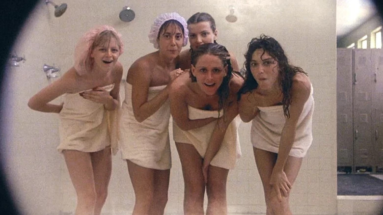 Un groupe de femmes enveloppées dans des serviettes regardent la caméra dans une salle de douche de Porky's.