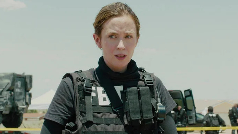 Kate Macer portant une chemise du FBI et un équipement tactique 