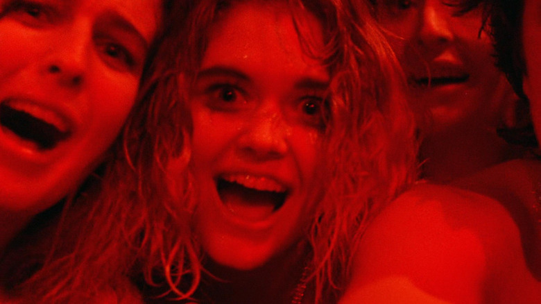 Trois filles riant sous un éclairage rouge dans Society (1989)