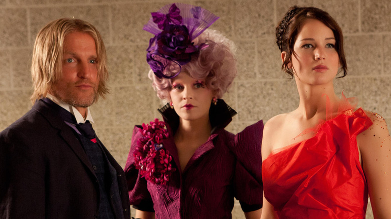 Effie, Haymitch et Katniss se tiennent devant un mur