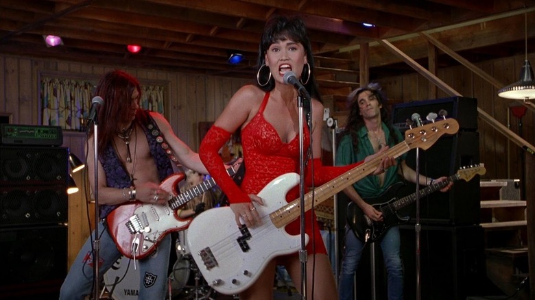 Tia Carrere dans le rôle de Cassandra jouant de la basse dans une robe rouge dans Wayne's World