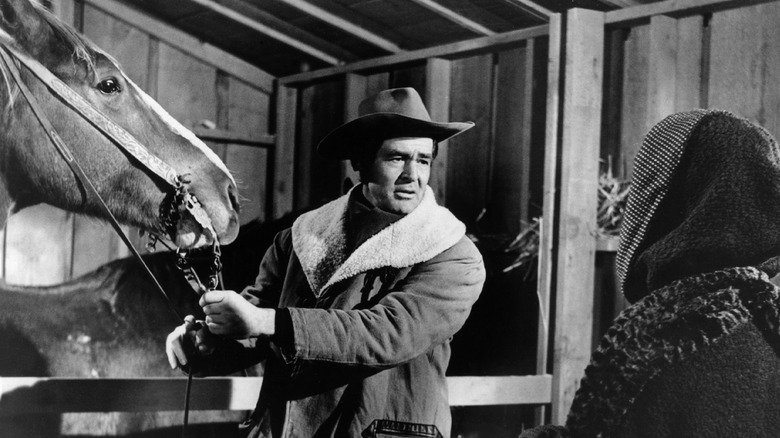 Blaise Starrett s'occupant d'un cheval tout en regardant Helen Crane dans Day of the Outlaw