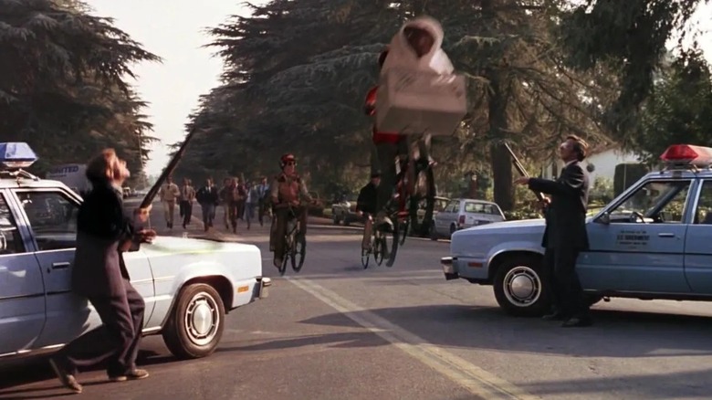 Elliot et ET décollent pendant que les flics tiennent des armes dans ET l'extraterrestre (1982)