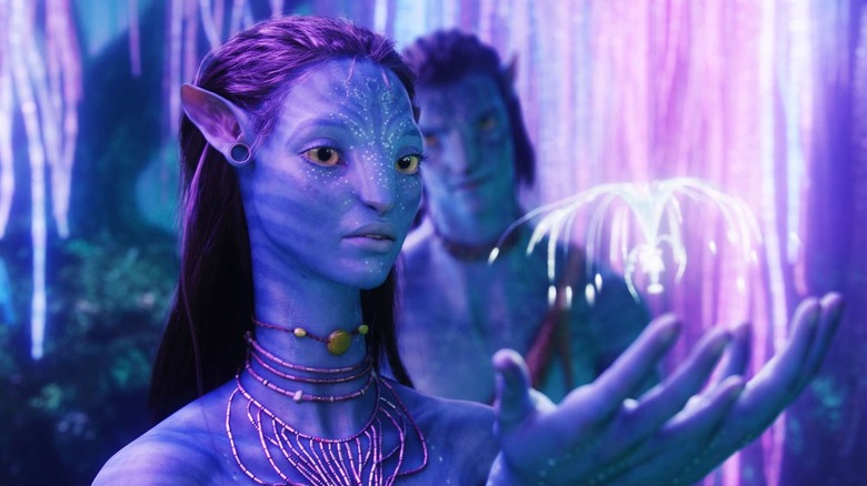 Neytiri s'occupant d'une créature extraterrestre tout en parlant à Jake Sully dans Avatar (2009)