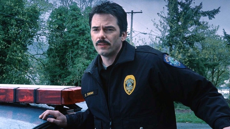 Charlie Swan s'appuyant sur une voiture de police