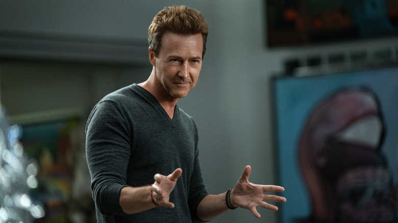 Miles Bron ricanant et gesticulant dans un pull gris de PDG technologique dans Glass Onion (2022)