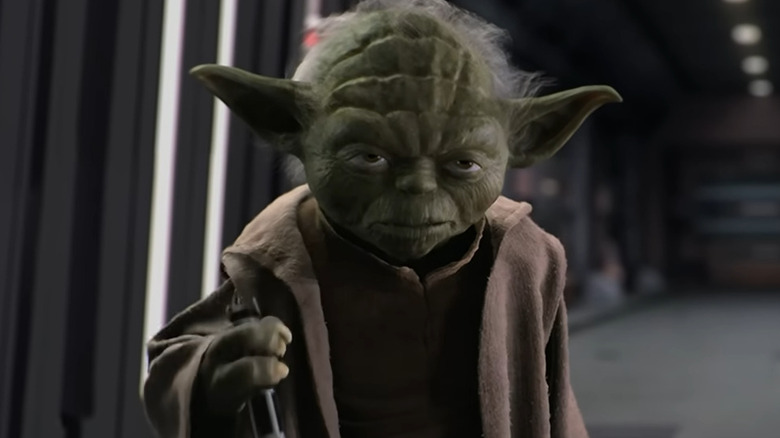 Yoda tenant la poignée d'un sabre laser