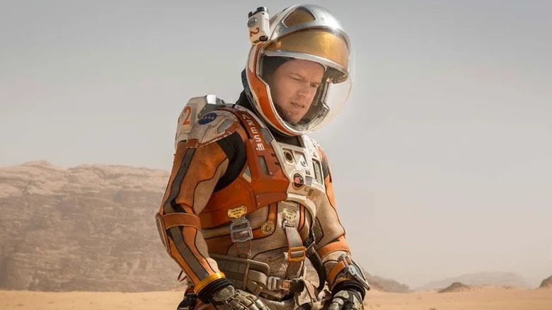 Mark Watney portant une combinaison spatiale et regardant vers le bas dans The Martian